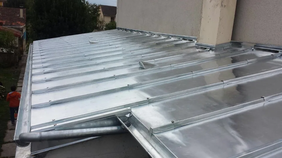 Habillage métallique et raccord au pied d’un mur.